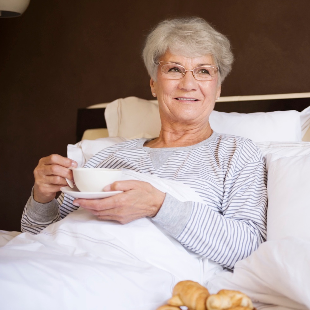 mujer mayor desayunando en la cama mujer mayor desayunando en la cama